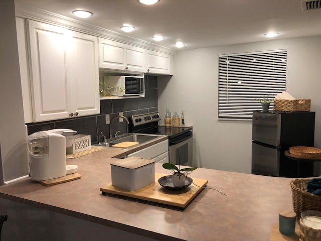 kitchen with white cabinets, appliances with stainless steel finishes, sink, and tasteful backsplash