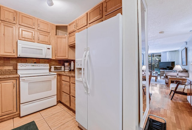 kitchen featuring light tile patterned floors, white appliances, a textured ceiling, and light brown cabinetry