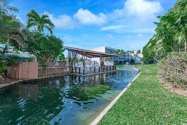 view of dock with a lawn and a water view