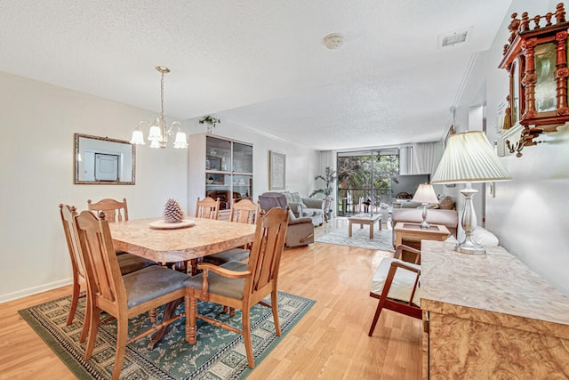 dining space with a chandelier, a textured ceiling, and light hardwood / wood-style flooring