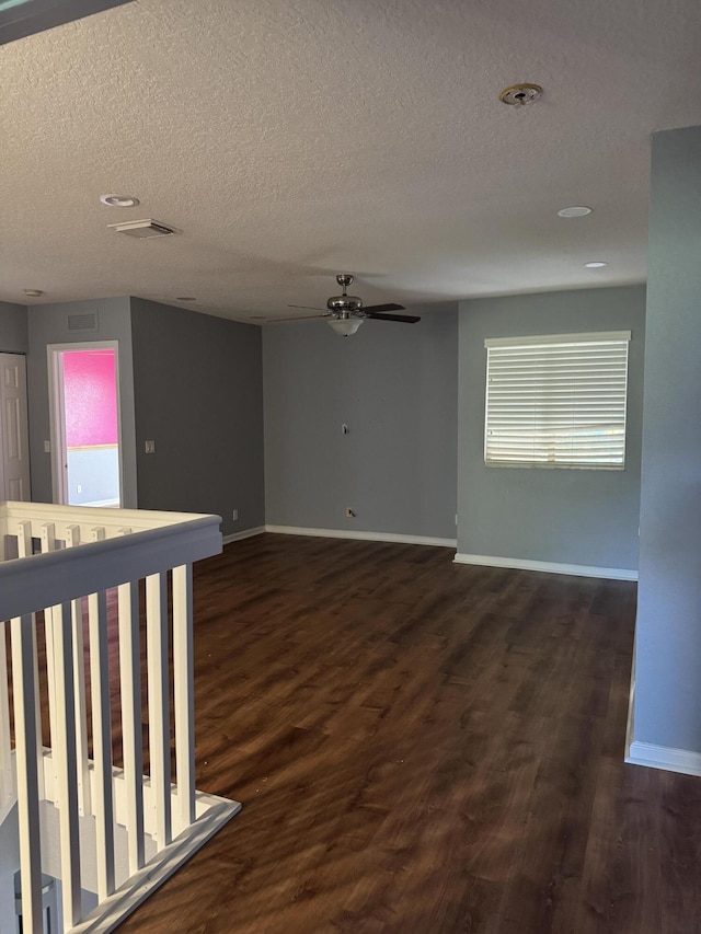 empty room with dark hardwood / wood-style flooring, a textured ceiling, and ceiling fan