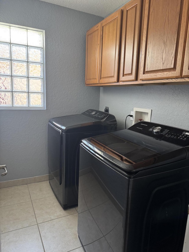 laundry room with washer and clothes dryer, light tile patterned floors, and cabinets