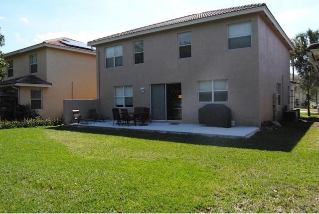 rear view of house featuring a yard, a patio, and solar panels