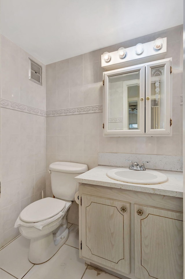 bathroom with tile walls, tile patterned flooring, vanity, and toilet