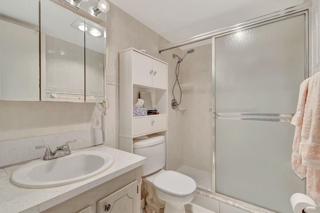 bathroom featuring vanity, toilet, and a shower with door