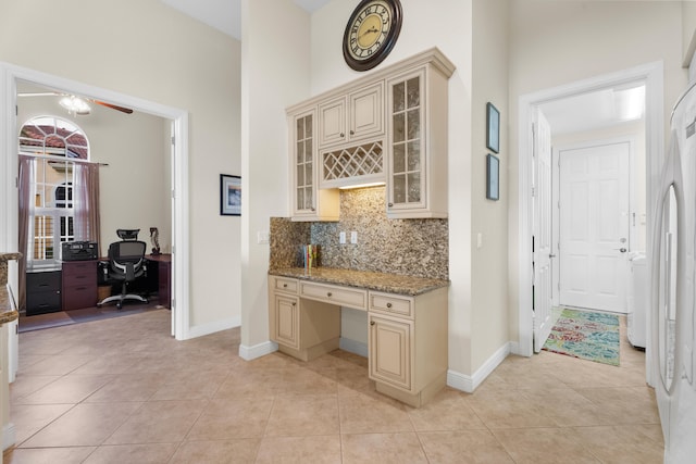 kitchen with light stone counters, ceiling fan, cream cabinetry, and backsplash