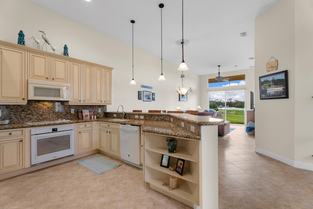 kitchen featuring backsplash, kitchen peninsula, pendant lighting, sink, and white appliances