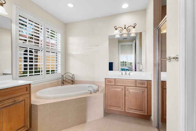 bathroom with vanity, tiled bath, tile patterned floors, and a healthy amount of sunlight