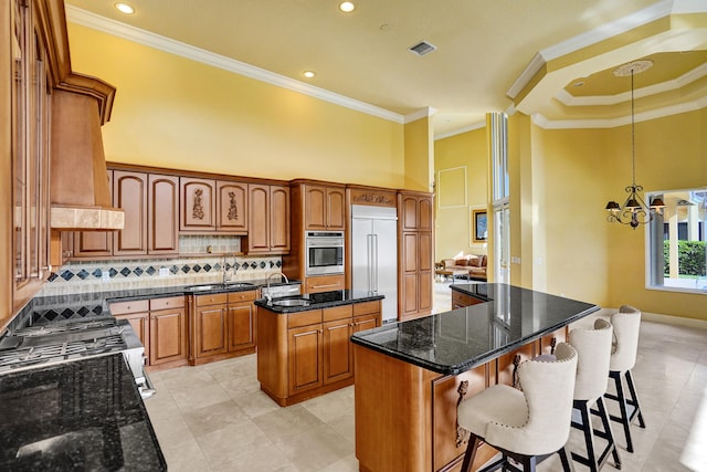 kitchen with stainless steel appliances, ornamental molding, dark stone counters, decorative light fixtures, and a center island