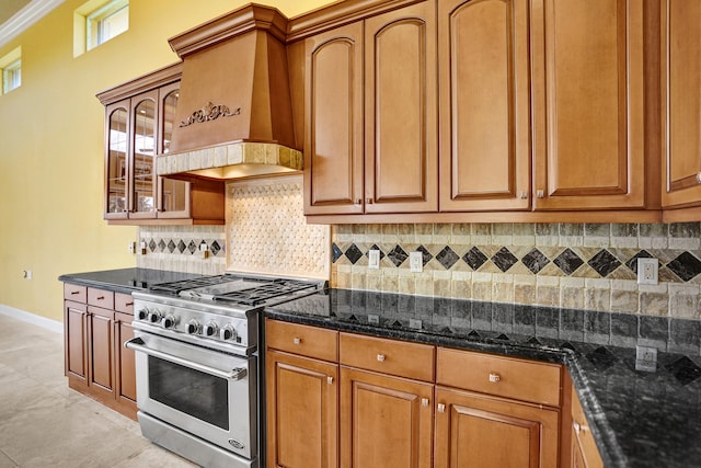 kitchen with ornamental molding, backsplash, stainless steel range, dark stone countertops, and custom exhaust hood