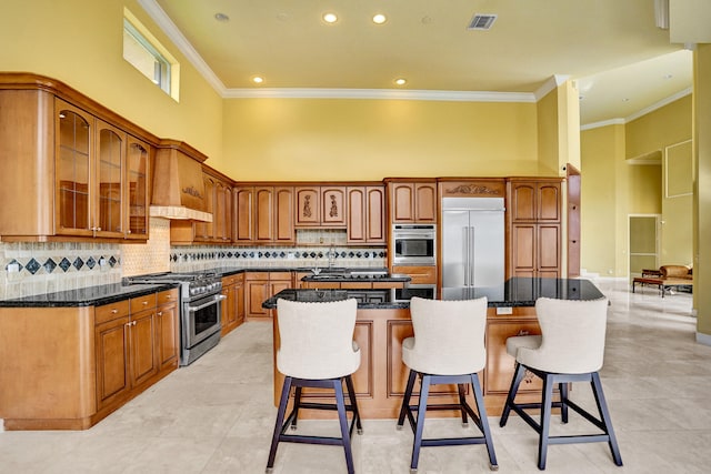 kitchen with premium appliances, a breakfast bar area, ornamental molding, and a center island