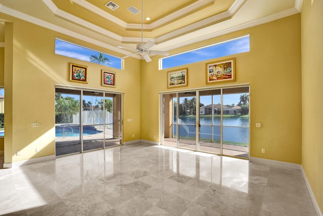 spare room with a towering ceiling, a water view, and ornamental molding