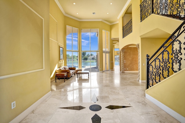 foyer entrance featuring ornamental molding, a water view, and a high ceiling