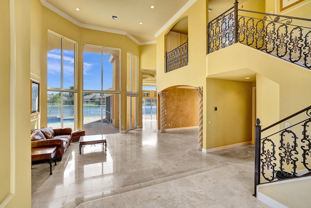 foyer entrance featuring a water view, ornamental molding, and a towering ceiling