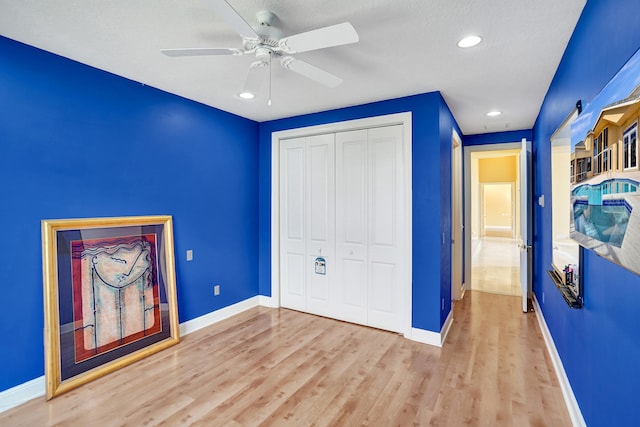 unfurnished bedroom with ceiling fan, a textured ceiling, a closet, and light hardwood / wood-style flooring