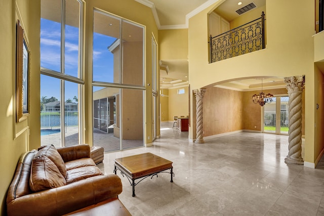 living room featuring ornate columns, a water view, crown molding, and a towering ceiling