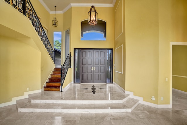 foyer with crown molding, a chandelier, and a high ceiling