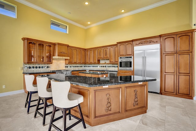 kitchen with dark stone counters, a kitchen island, a high ceiling, and stainless steel appliances