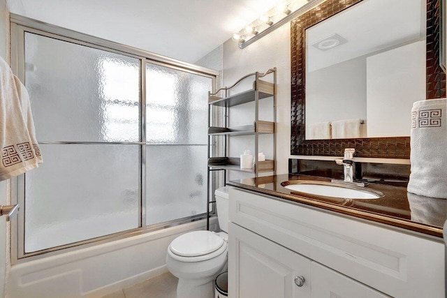 full bathroom featuring tile patterned floors, backsplash, vanity, bath / shower combo with glass door, and toilet