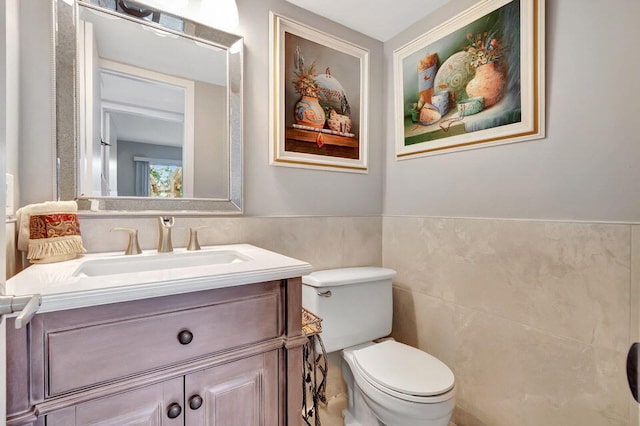 bathroom featuring toilet, vanity, and tile walls