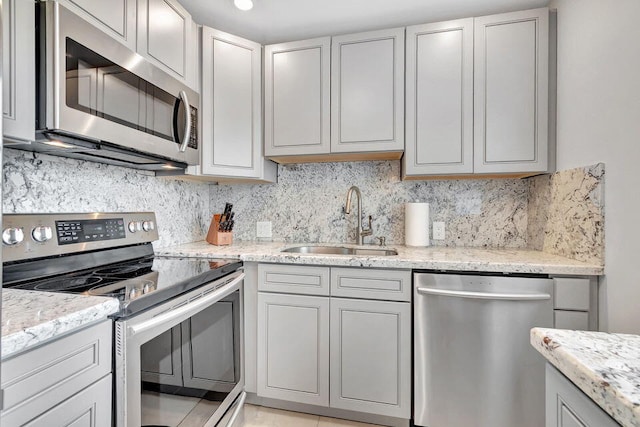 kitchen with stainless steel appliances, sink, light stone counters, and tasteful backsplash