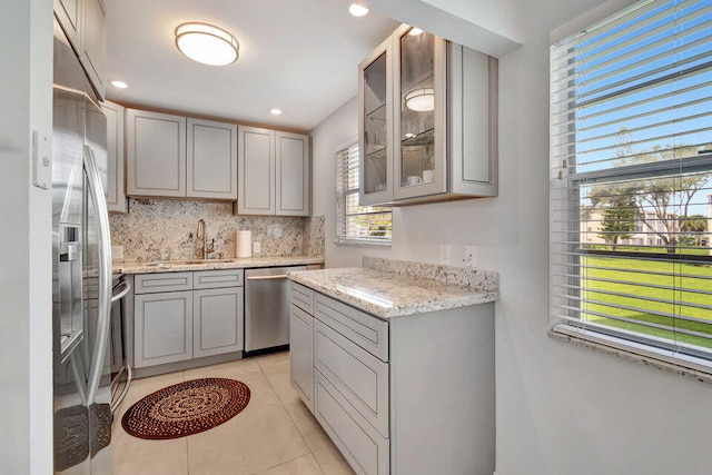 kitchen featuring stainless steel appliances, decorative backsplash, light tile patterned floors, sink, and gray cabinetry