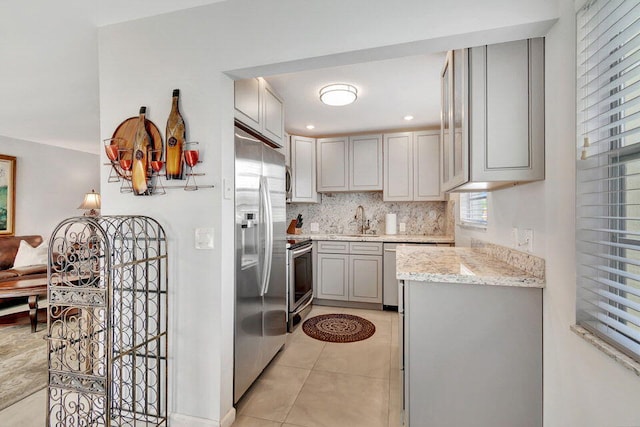 kitchen featuring stainless steel appliances, sink, light tile patterned floors, gray cabinets, and backsplash