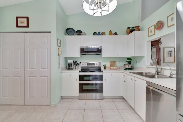 kitchen with high vaulted ceiling, white cabinets, sink, light tile patterned floors, and stainless steel appliances