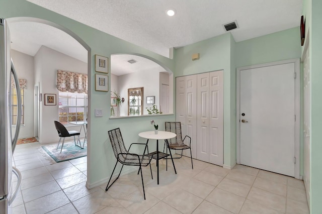 dining area with light tile patterned floors, a textured ceiling, and lofted ceiling