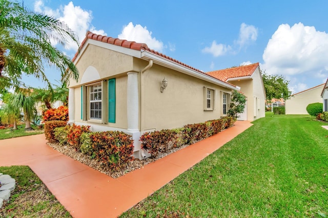 view of property exterior with stucco siding, a tile roof, and a yard