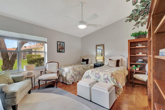 bedroom featuring a textured ceiling, light hardwood / wood-style floors, ceiling fan, and lofted ceiling