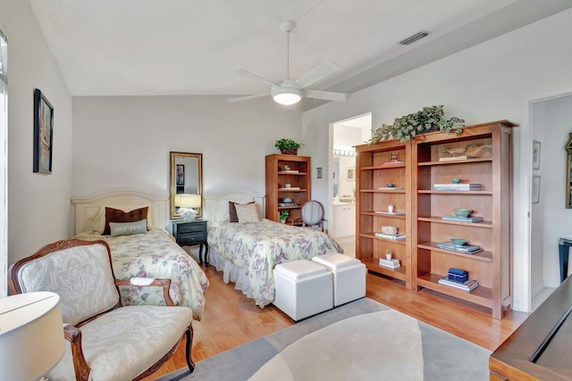 bedroom featuring ceiling fan, light wood-type flooring, lofted ceiling, and ensuite bath