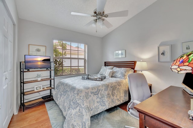 bedroom featuring vaulted ceiling, light hardwood / wood-style flooring, ceiling fan, a textured ceiling, and a closet