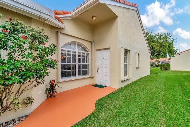 view of exterior entry featuring a yard