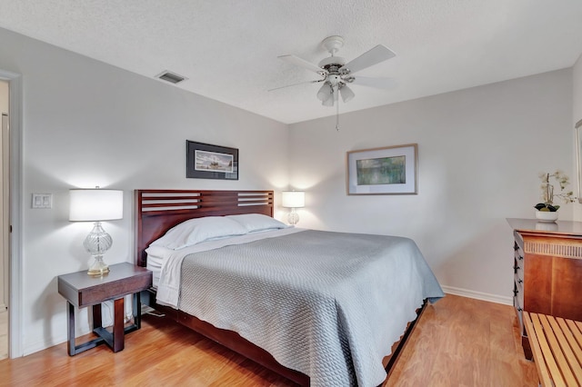 bedroom featuring a textured ceiling, light wood-type flooring, and ceiling fan