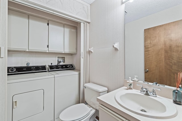 bathroom featuring vanity, washing machine and dryer, a textured ceiling, and toilet