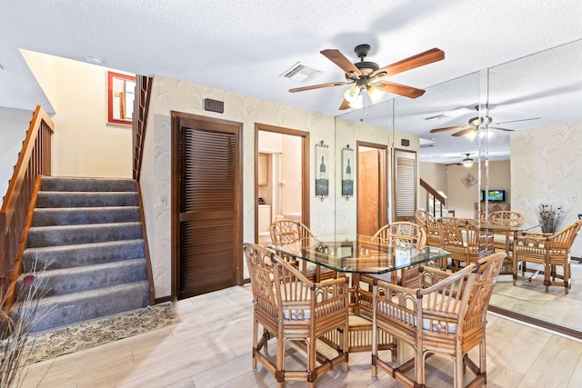 dining room featuring light wood-type flooring and a textured ceiling