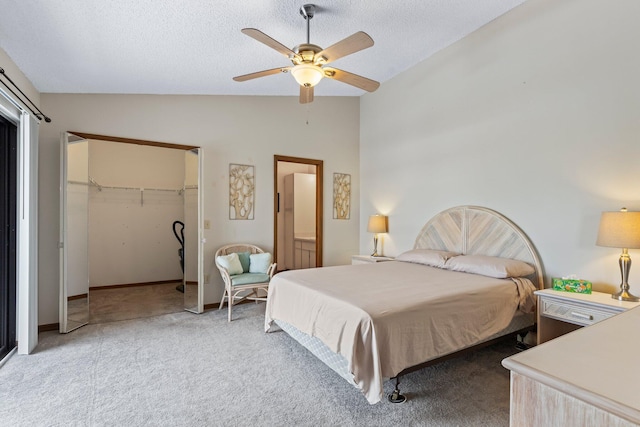 carpeted bedroom featuring vaulted ceiling, a textured ceiling, ceiling fan, a closet, and a spacious closet