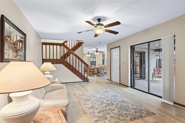 living room featuring a textured ceiling, light hardwood / wood-style flooring, and ceiling fan