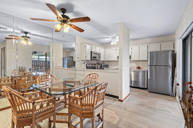 dining room with ceiling fan, a textured ceiling, and light wood-type flooring