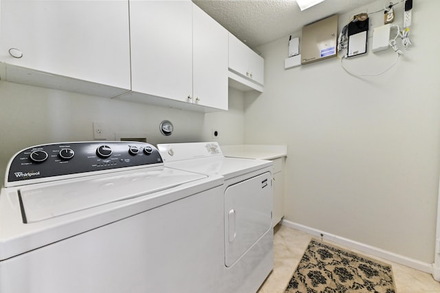 laundry room with washer and dryer, light tile patterned flooring, cabinets, and a textured ceiling