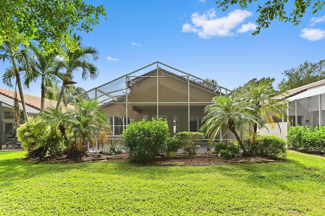 back of property featuring glass enclosure and a lawn