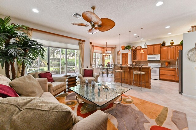 tiled living room with a textured ceiling and ceiling fan