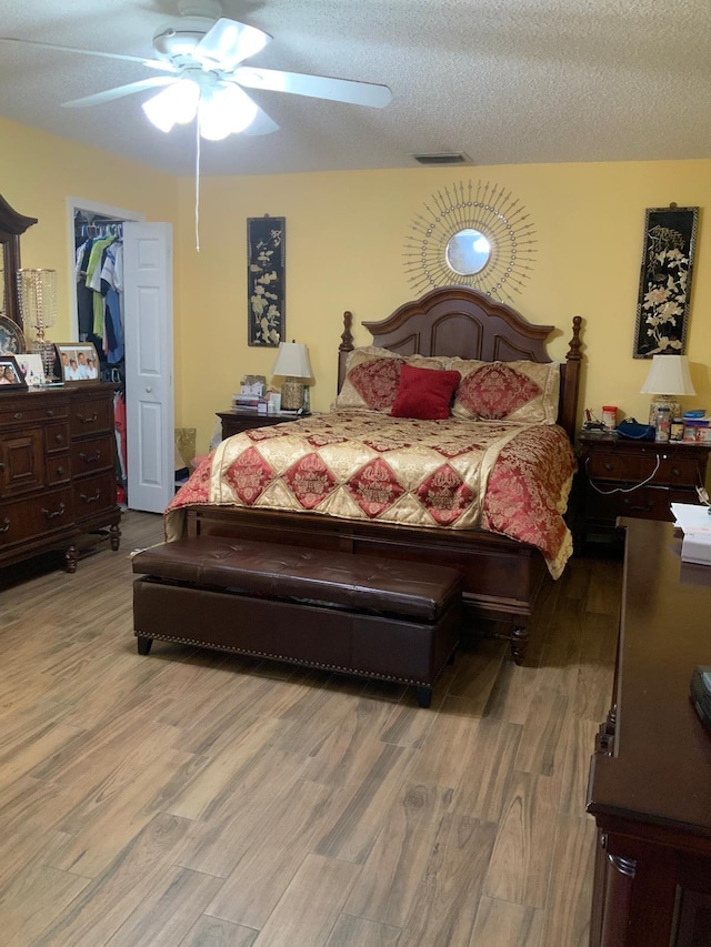 bedroom featuring hardwood / wood-style flooring, ceiling fan, and a textured ceiling