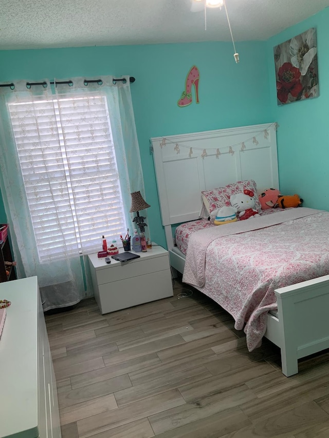 bedroom with a textured ceiling and light wood-type flooring