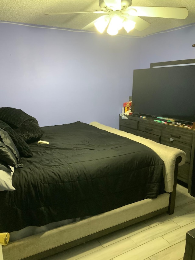 bedroom with a textured ceiling, light hardwood / wood-style floors, and ceiling fan