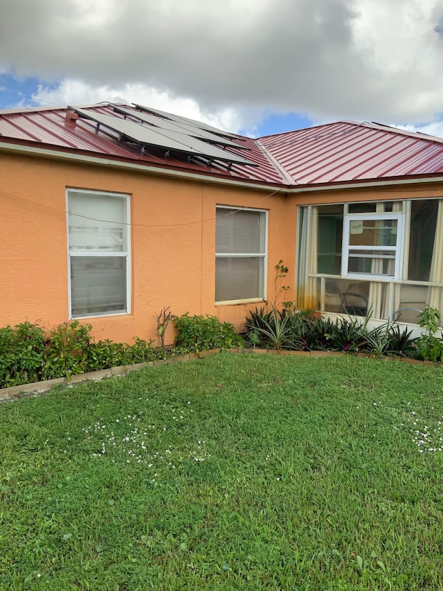 view of home's exterior featuring solar panels and a lawn