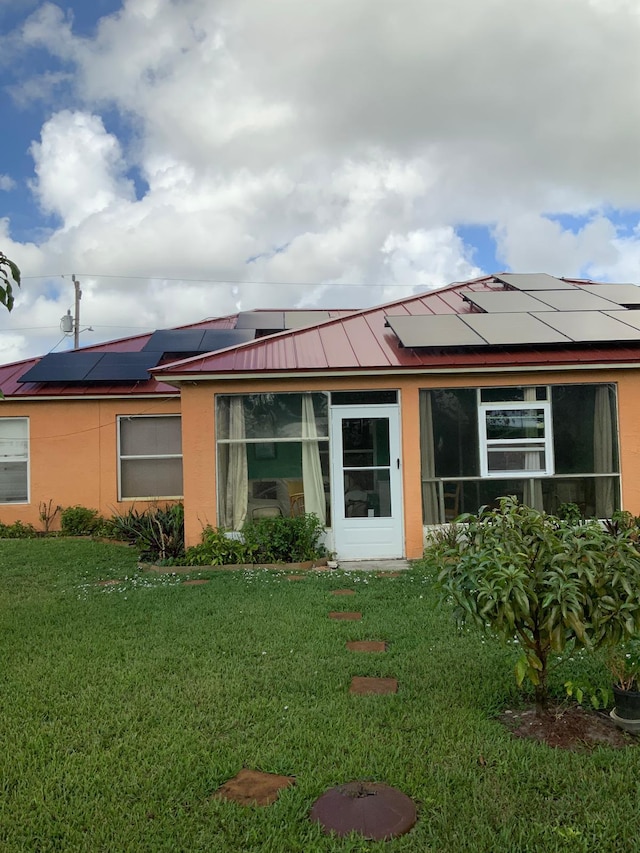 rear view of house with a yard and solar panels