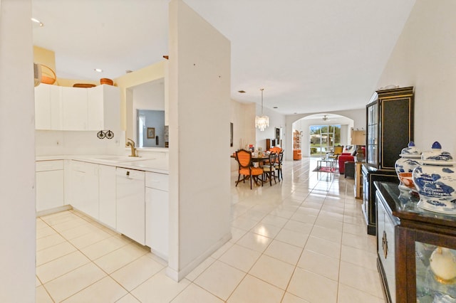 kitchen with white cabinets, dishwasher, light tile patterned floors, and a notable chandelier