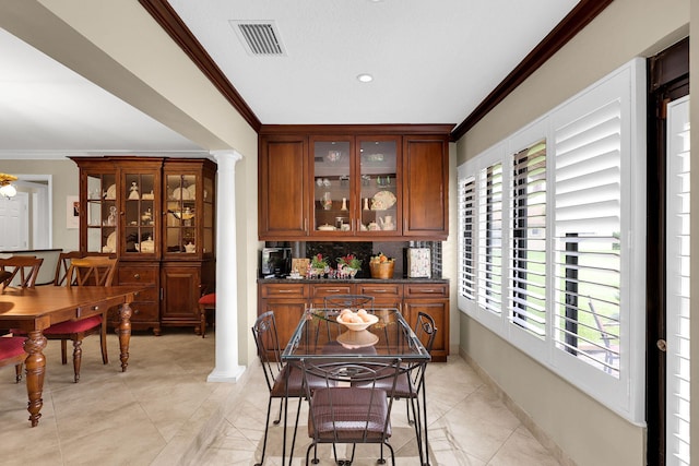 bar featuring light tile patterned floors, ornate columns, backsplash, and crown molding